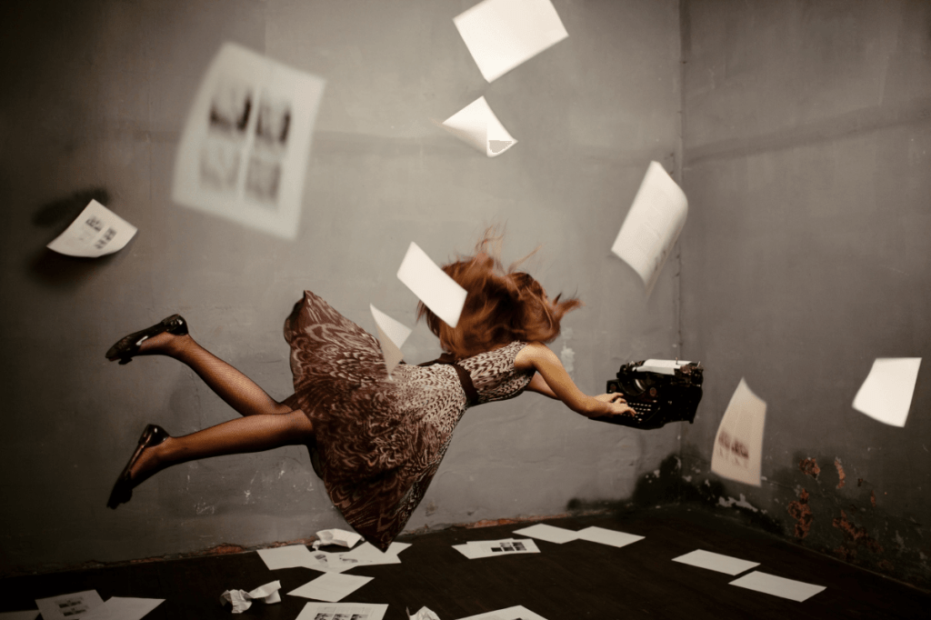lady flying in the air trying to catch a typewriter surrounded by paper